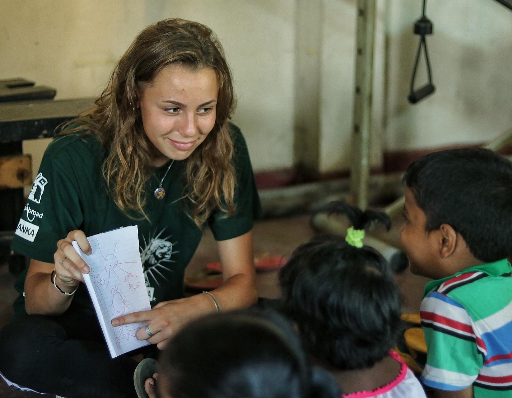 Female Childcare volunteer teaches English language skills to children at a kindergarten in Sri Lanka. Projects Abroad volunteer with children in Sri Lanka teaches English to young children at her Childcare placement.